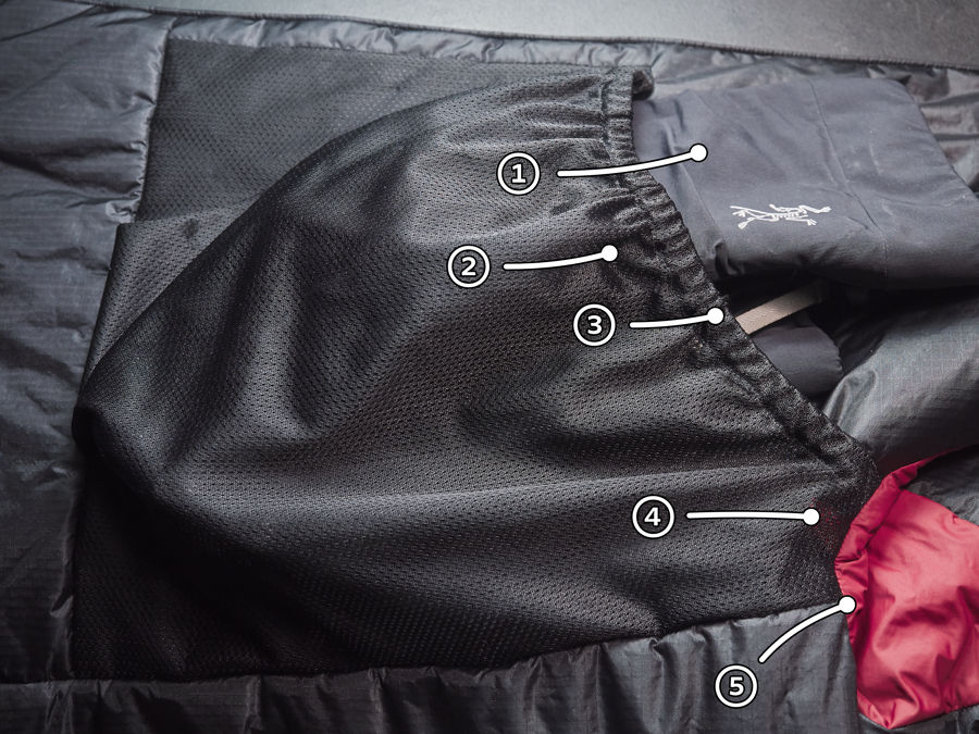 A photo of the Dually drop pocket. It is a black mesh pocket, straight on three sides (left, top, bottm of frame). The right side in frame is a slanted opening, with the gloves poking out.