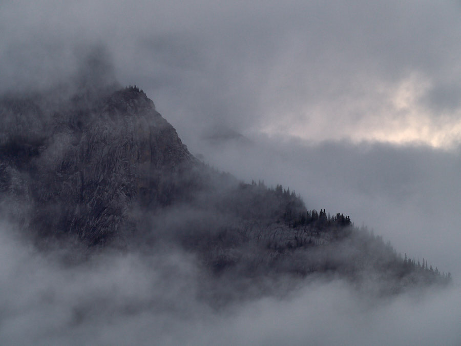 Photo of a mountain peeking through cloud cover.